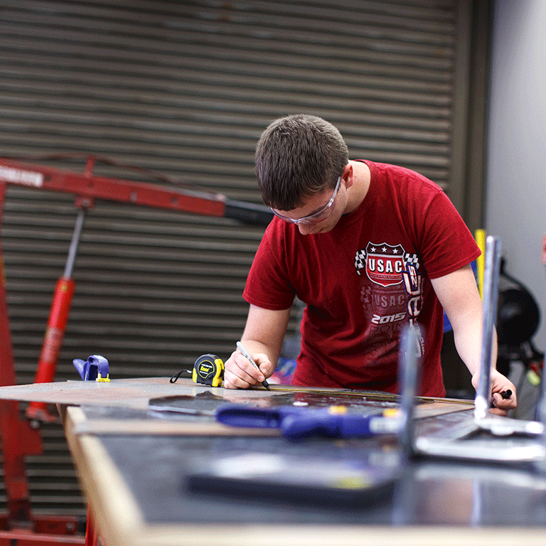 A photo of a motorsports engineering student working in the motorsports garage.